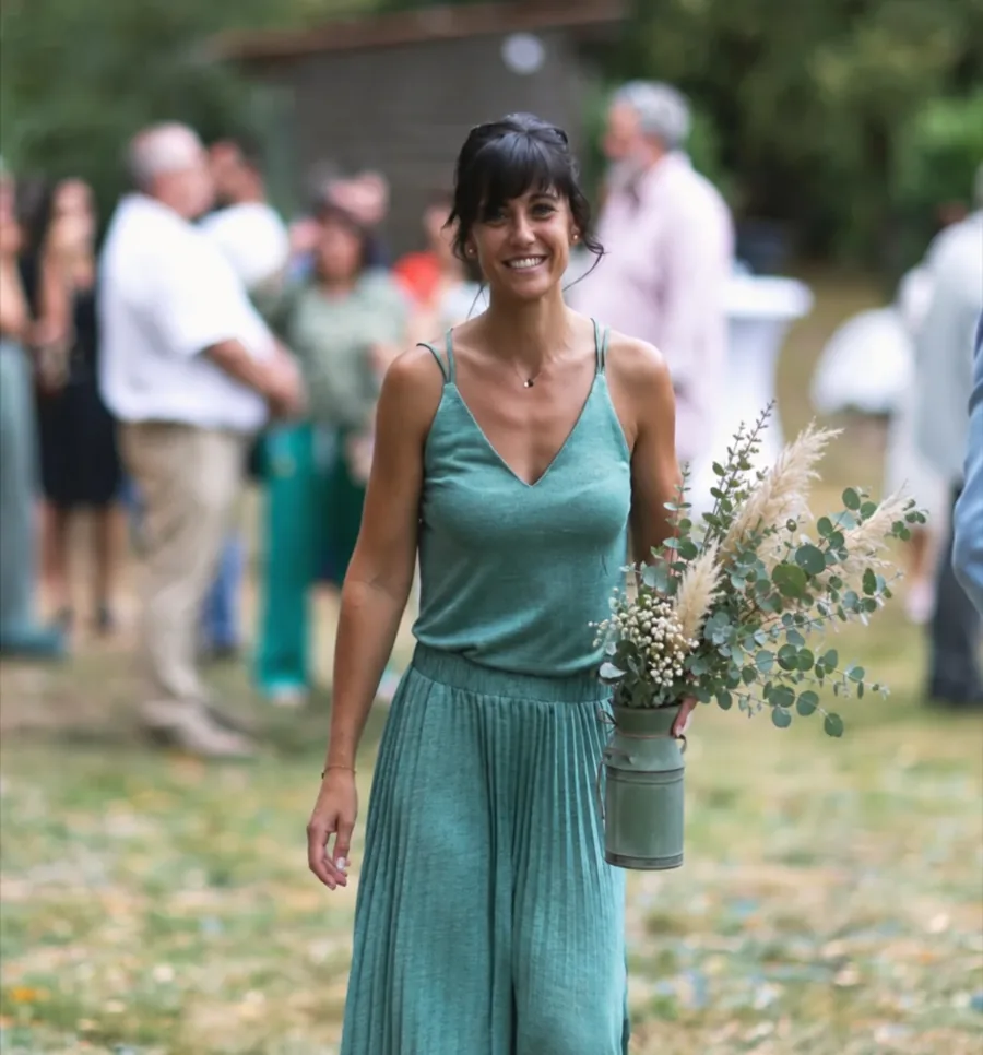 Aurore, fondatrice d'Orore Event, souriante avec un bouquet d'eucalyptus et de pampa lors d'une réception en extérieur