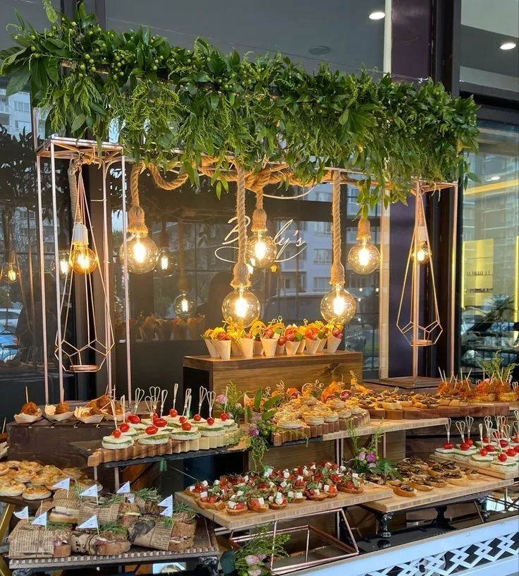 Buffet cocktail raffiné sous suspensions lumineuses pour un départ à la retraite