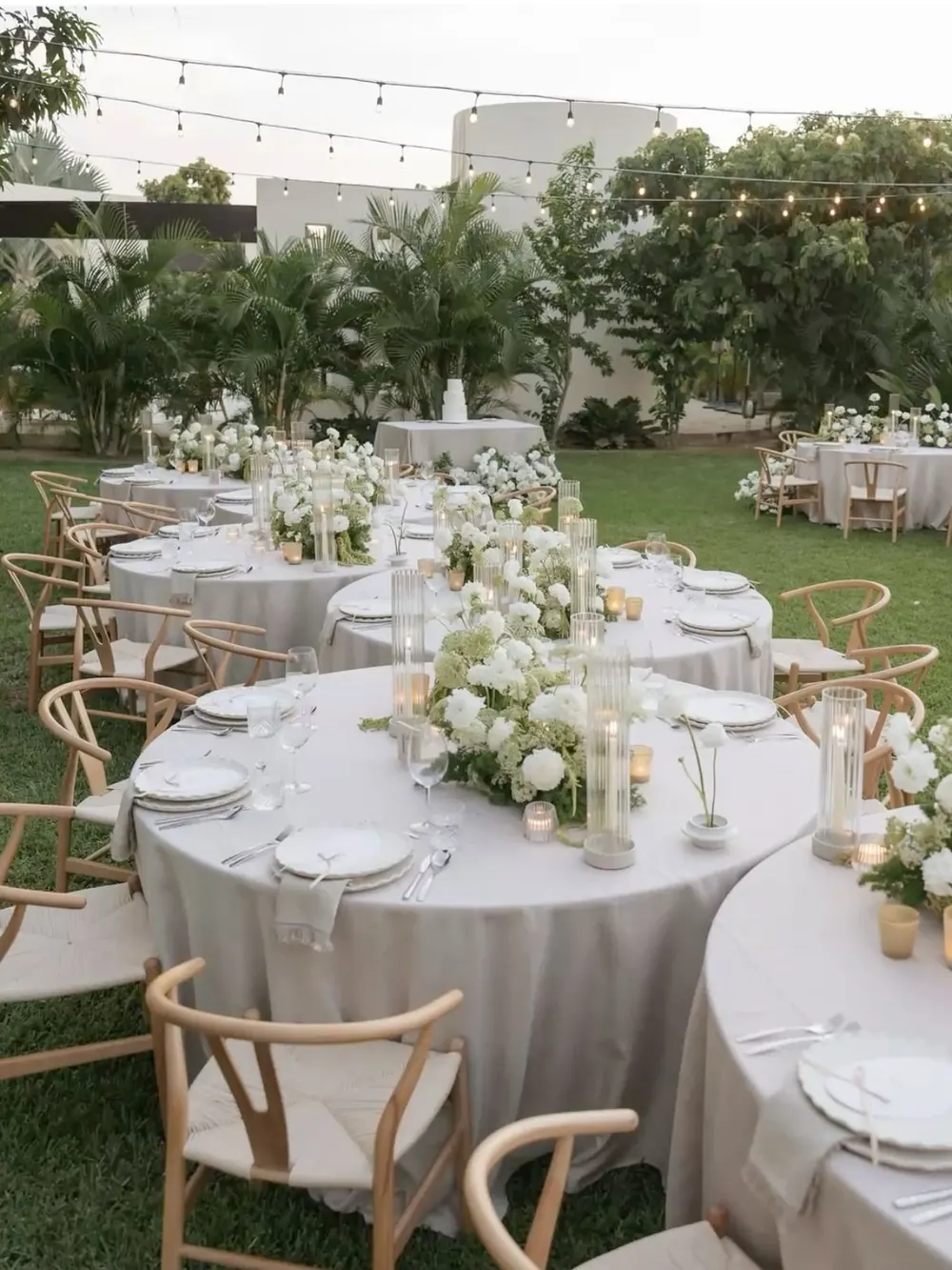 Réception de mariage en plein air avec tables rondes, fleurs blanches et guirlandes lumineuses près de Bordeaux